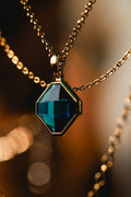 Gold tone necklace with faceted teal gemstone pendant