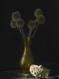Antique engraved brass vase with dried flowers on dark background
